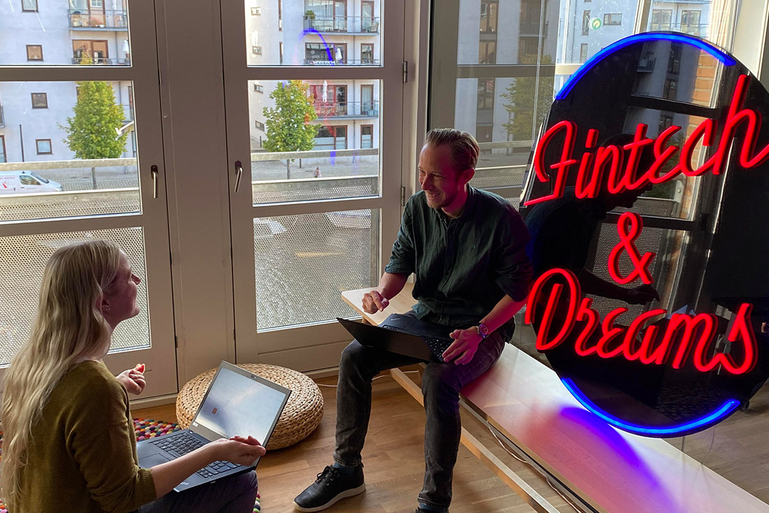 Crediwire team sat next to a sign reading Fintech & Dreams
